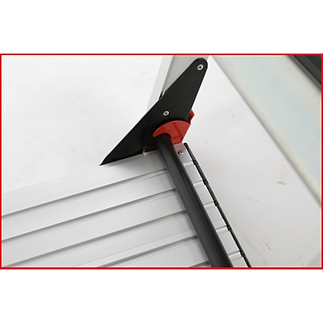 Detailaufnahme eines schwarzen und roten Werkzeugs an einer weißen Oberfläche mit metallischen Leisten.